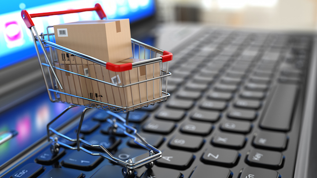 E-commerce. Shopping cart with cardboard boxes on laptop. 3d