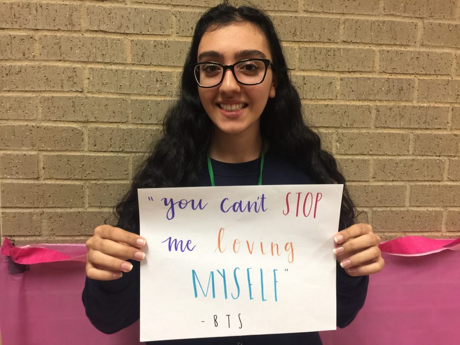 Ashley Farokhrouz holds up a popular song quote about self-love.