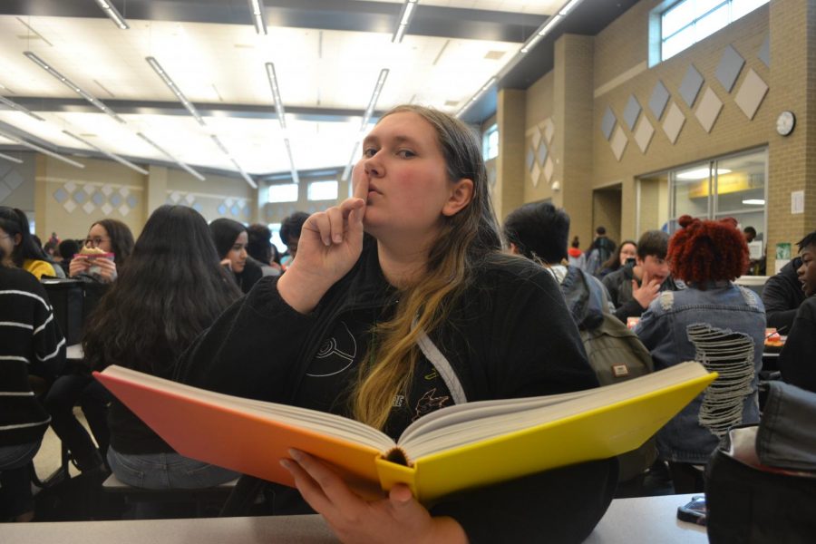 A student suspiciously reads a book that is most likely banned at their school.