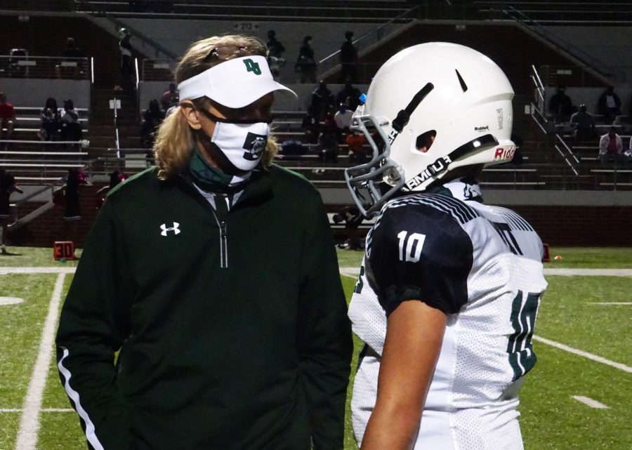 Football coach Shawn Alsup talks with one of his players during a game Oct. 13. Players and coaches have to wear masks during a game.